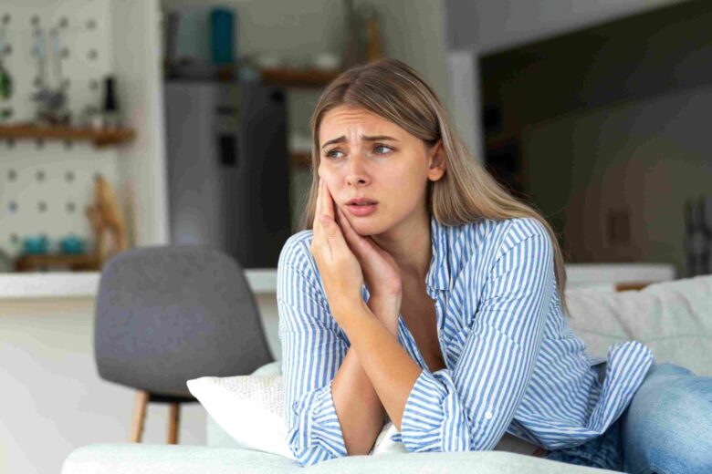 Person holding their cheek in discomfort, illustrating tooth sensitivity and possible dental pain.