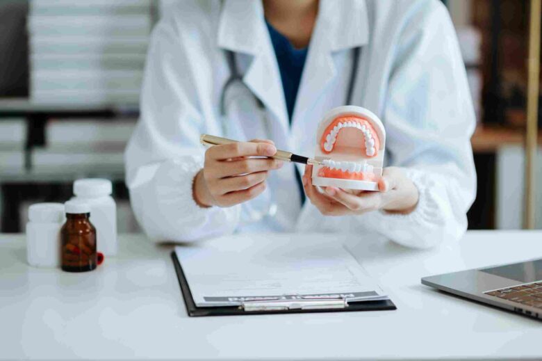 Dentist holding a dental model and explaining common causes and treatment options for tooth sensitivity