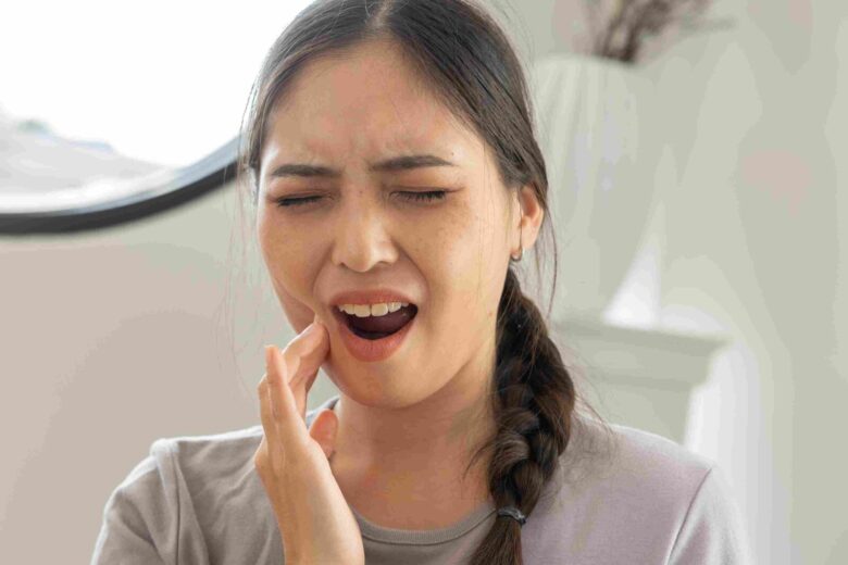 Person holding their jaw in pain, illustrating tooth sensitivity and dental discomfort