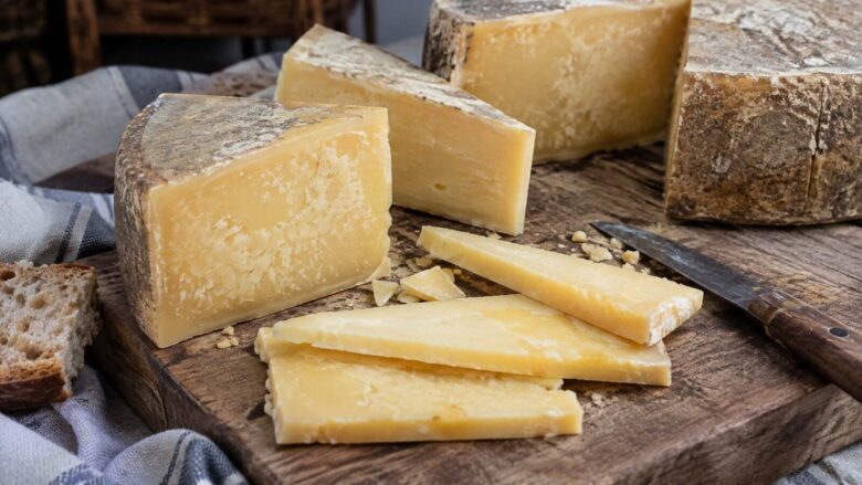 Traditional Livanjski sir cheese cut into wedges and slices on a rustic wooden board with a knife.